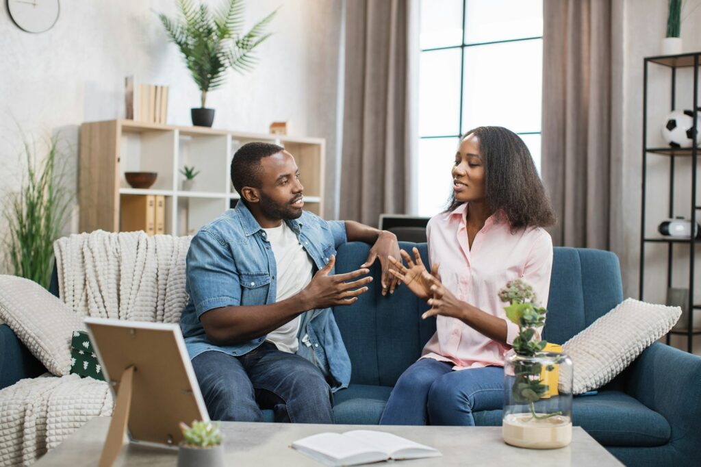 African american couple sitting on couch and chatting