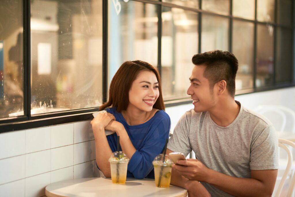 Asian Couple Talking In Modern Cafe