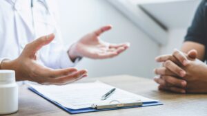 Doctor having conversation with patient while discussing explaining symptoms or counsel diagnosis