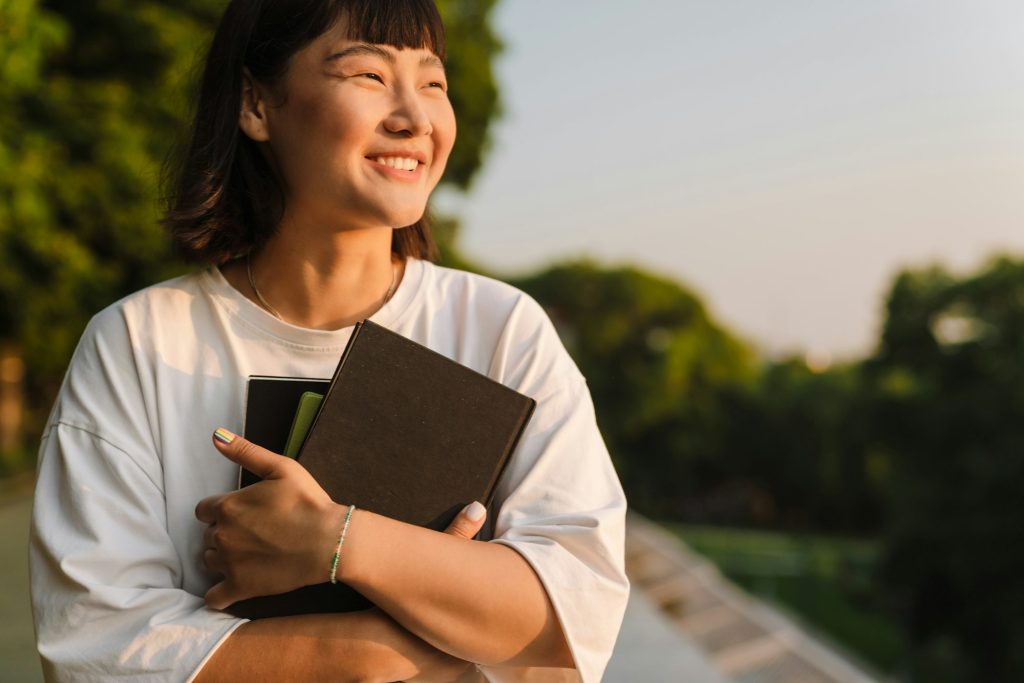 Smiling young asian woman walking in a green park
