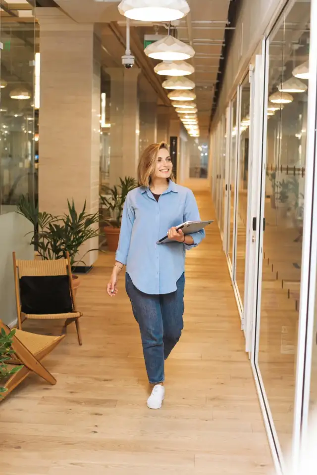 A professional walking through a bright office hallway