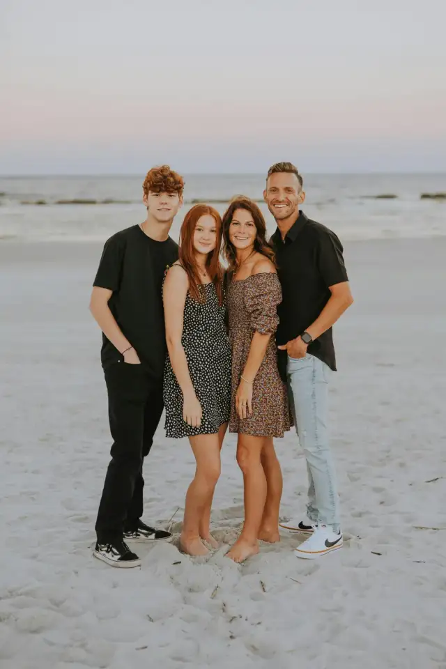 A family of four standing together on a beach